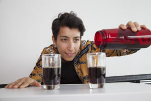 Bilde som viser en kvinne som slår like mengder drikke opp i to glass.